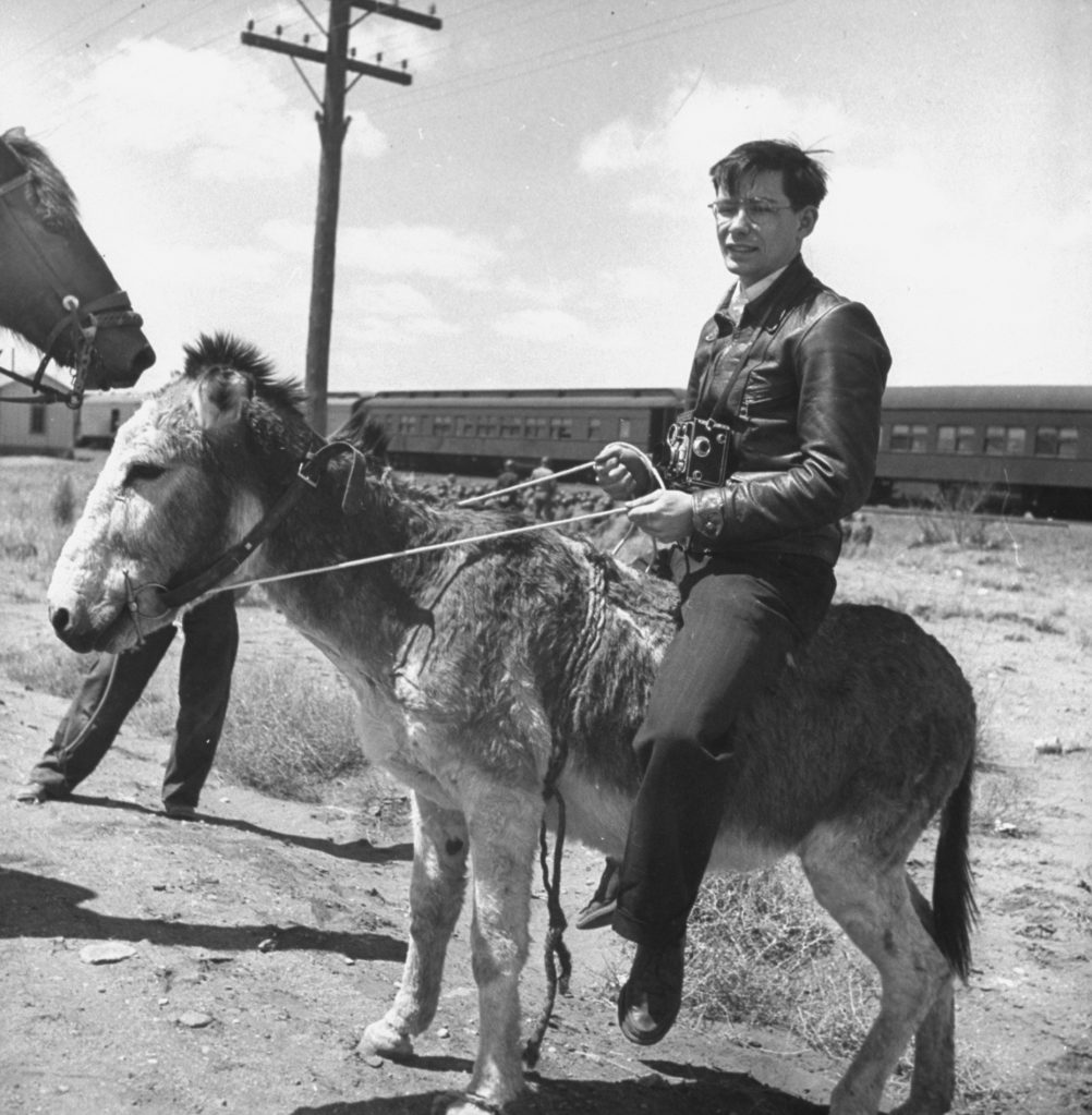 Myron Davis riding a burro while covering a story about a US troop train. (Photo by Myron Davis/The LIFE Picture Collection © Meredith Corporation)