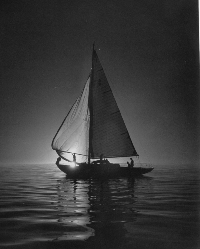 Full sails during a night sailboat race, with the sun peeking over the horizon. (Photo by Cornell Capa/The LIFE Picture Collection © Meredith Corporation)