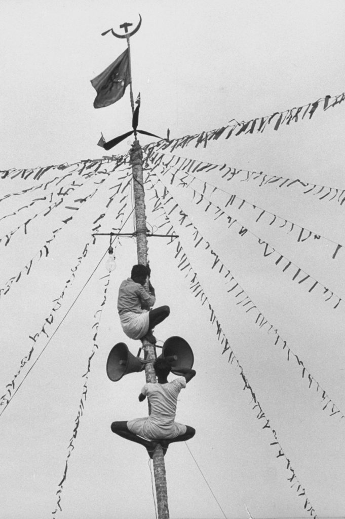 Communist workers fixing loudspeaker on a stripped coconut tree during the Travancore-Cochin elections. (Photo by James Burke/The LIFE Picture Collection © Meredith Corporation)