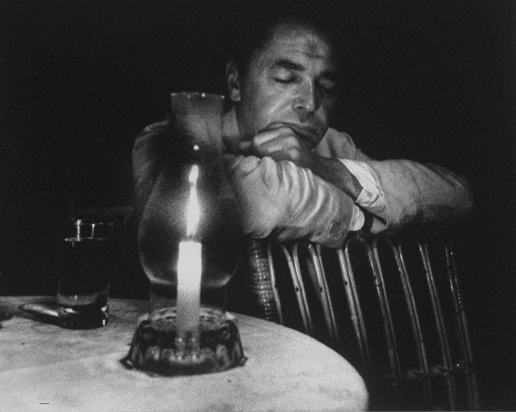 Eliot Elisofon, his eyes closed and his face illuminated by candle. (Photo by Gjon Mili/The LIFE Picture Collection © Meredith Corporation)