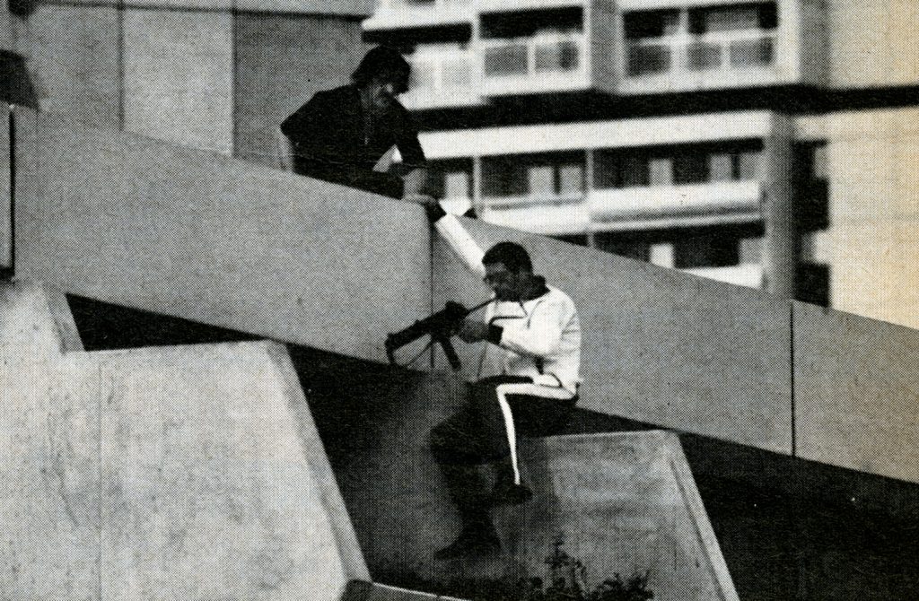 Perched on a terrace directly above the Israeli quarters, a German policeman checks his submachine gun before advancing further, Munich, September 1972.