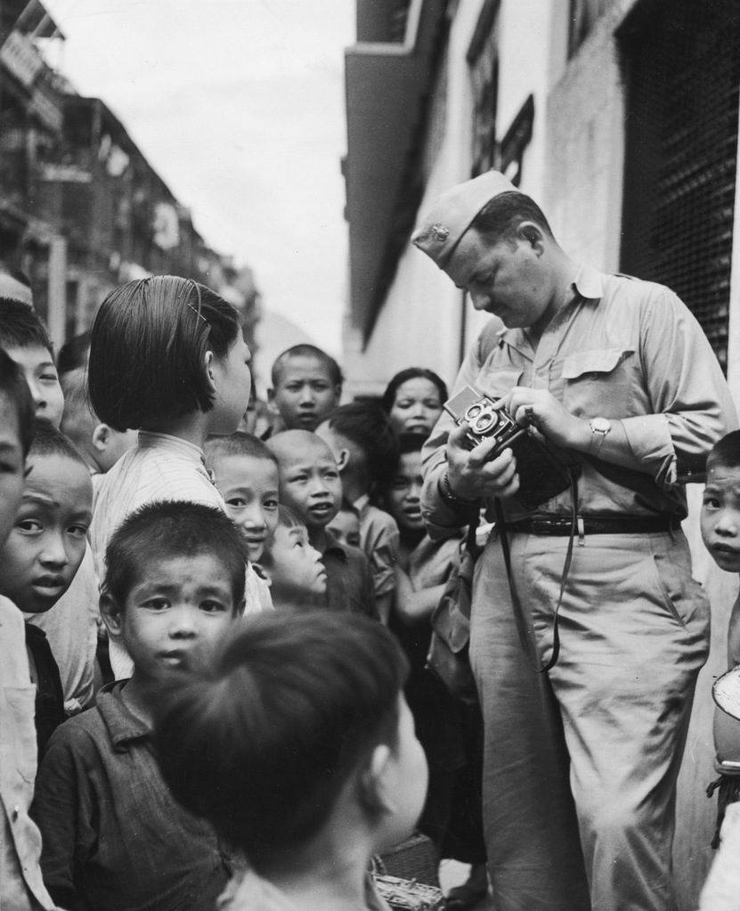 Photographer John Florea surrounded by Chinese children in a Queen's Road marketplace. (Photo by John Florea/The LIFE Picture Collection © Meredith Corporation)