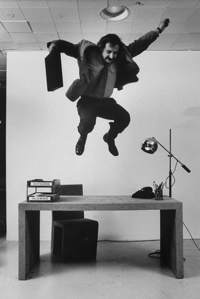Frank Gehry jumps on a desk   part of his line of cardboard furniture   in 1972.