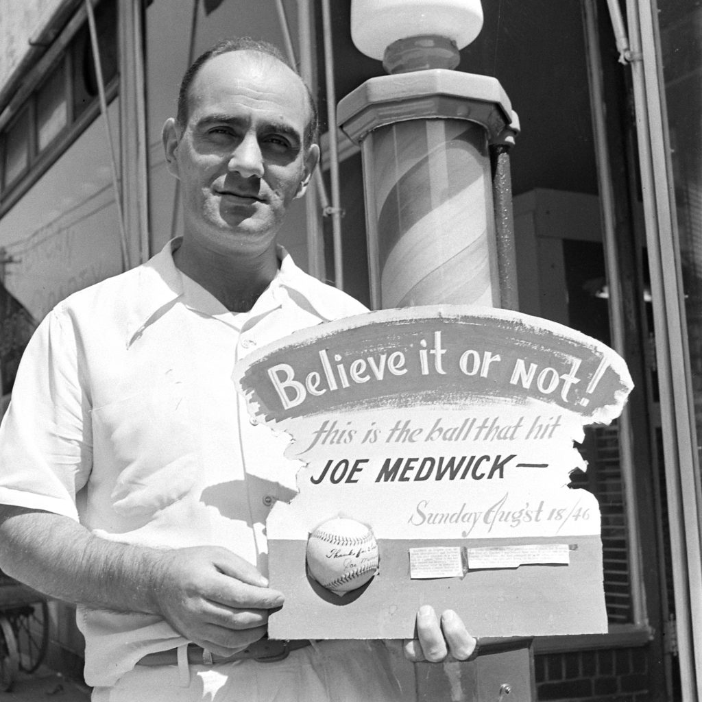 Jack Kaufman outside his barber shop on Rogers Avenue in Brooklyn in 1946, holding a signed baseball that once beaned future Hall of Famer Joe Medwick.