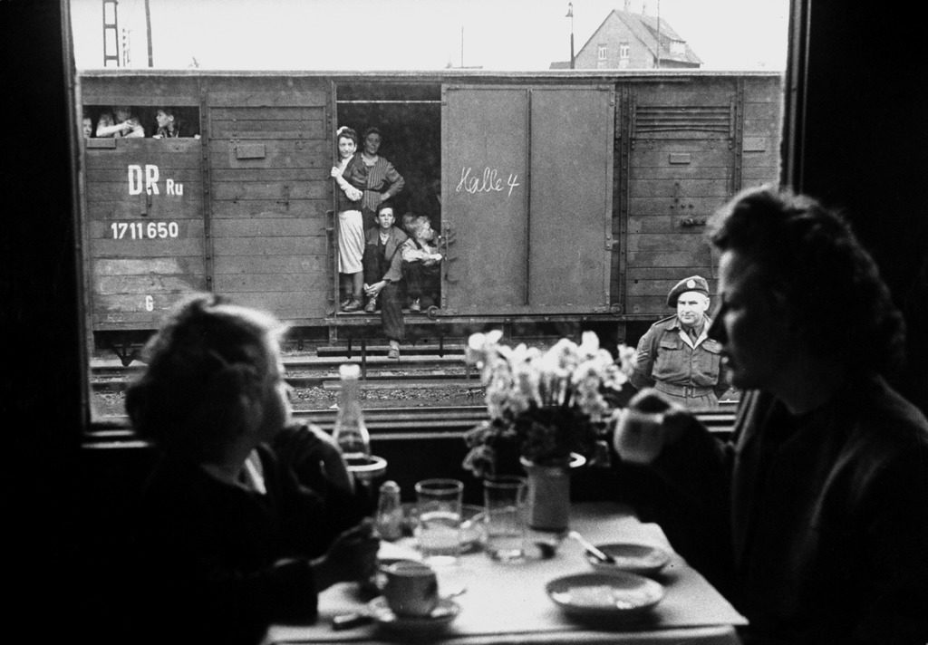 Wife and daughter of a US soldier sitting in a first class dining car looking out at German "expels" travelling in boxcars. (Photo by Walter Sanders/The LIFE Picture Collection © Meredith Corporation)