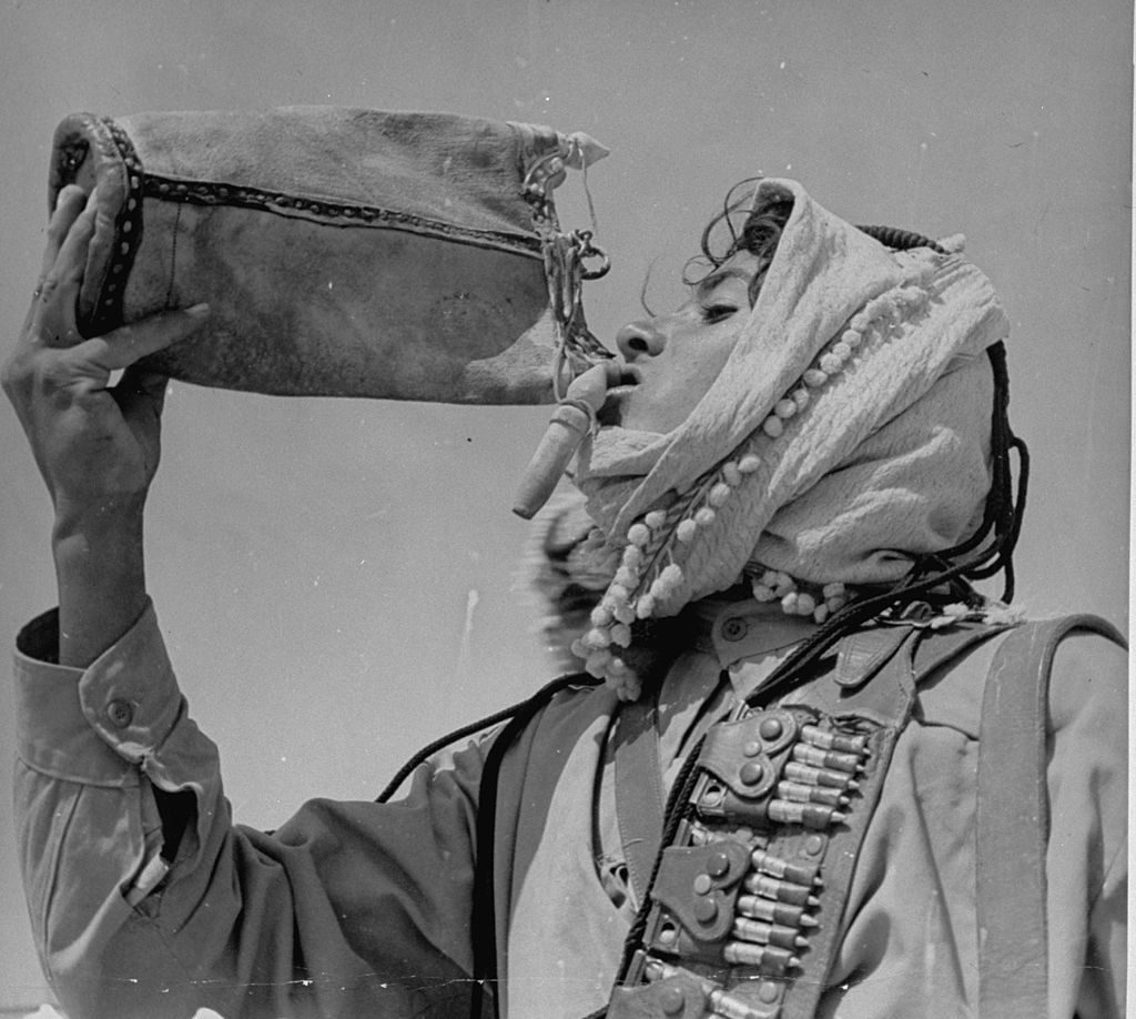 An Arabian showing off his head-dress while taking a drink of water. (Photo by James Jarche/The LIFE Picture Collection © Meredith Corporation)