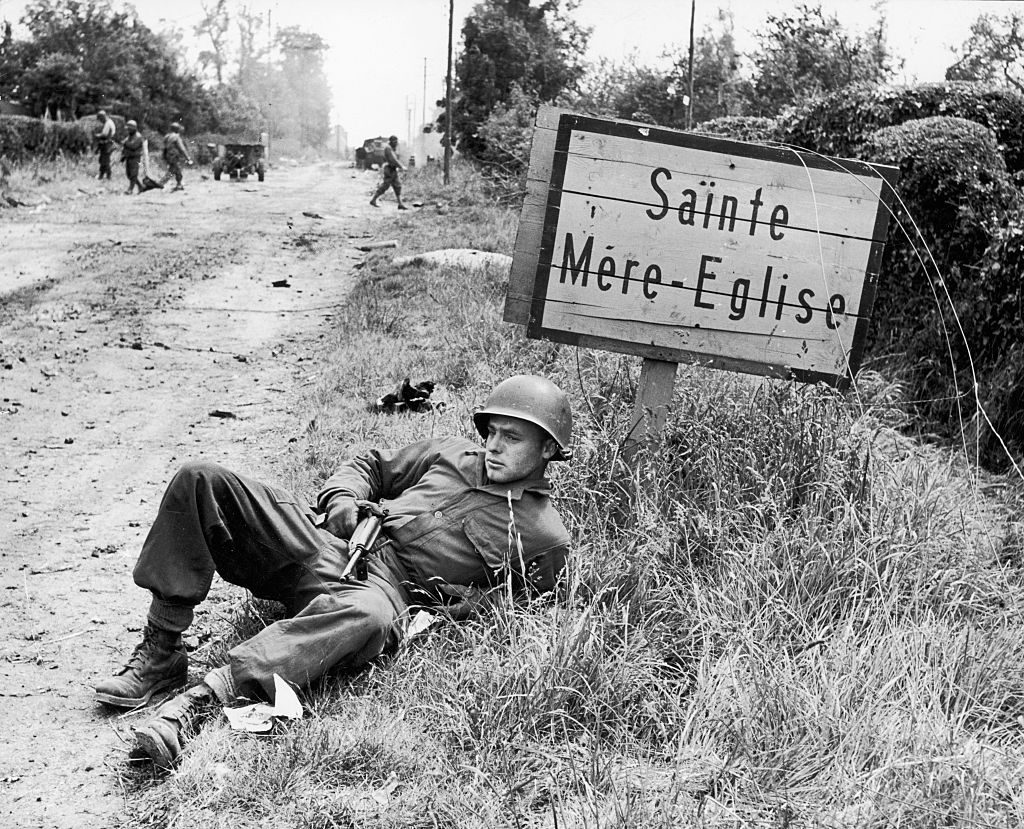 American soldier Elmer Habbs of Delaware resting next to signpost for the French town of Ste. Mere-Eglise as troops advance on the 2nd day of the Allied invasion of Normandy. (Photo by Bob Landry/The LIFE Picture Collection via © Meredith Corporation)