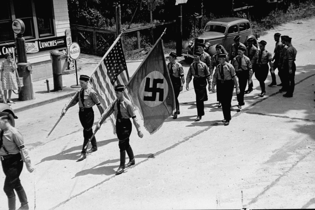 American Nazi party members, (aka German American Bund) march while carrying Nazi and American flags during a Bund outing from nearby Camp Sigfried. (Photo by Rex Hardy/The LIFE Picture Collection © Meredith Corporation)
