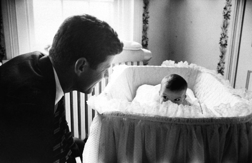 Senator John F. Kennedy playing peek-a-boo with his daughter Caroline in her crib. (Photo by Edward Clark/The LIFE Picture Collection © Meredith Corporation)