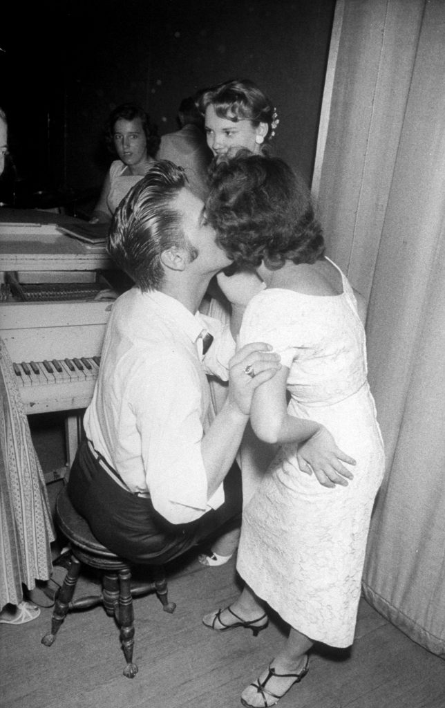 Elvis Presley tenderly kissing the cheek of a female admirer backstage before his concert, 1956.