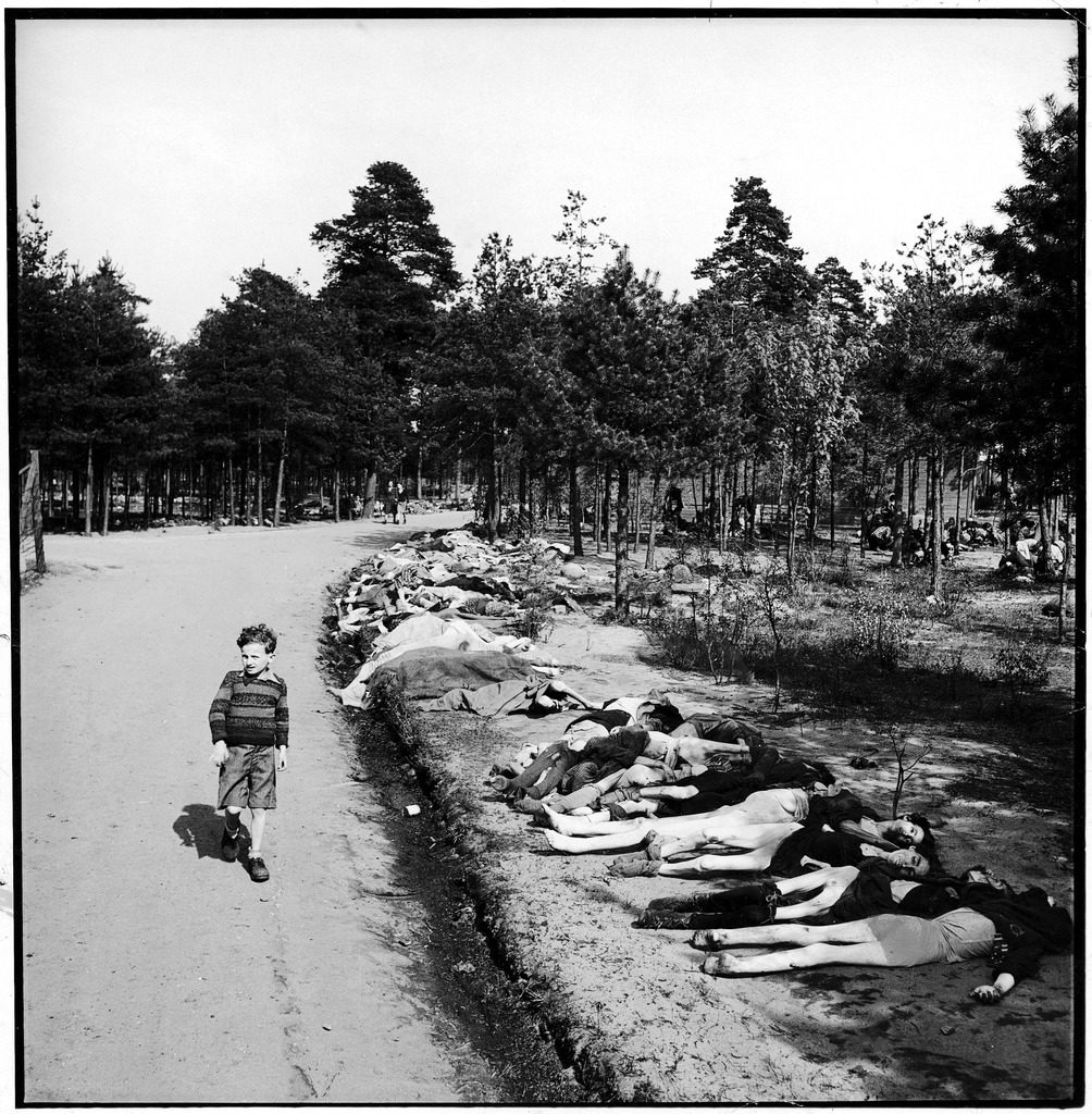 German boy walking down a dirt road lined with the corpses of hundreds of prisoners who have died of starvation near Bergen extermination camp.(Photo by George Rodger/The LIFE Picture Collection © Meredith Corporation)