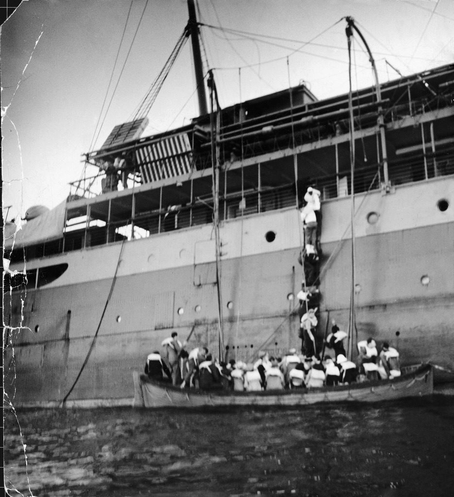 People climbing down a ladder, trying to board an already overfull lifeboat, as the SS Zam Zam sinks. (Photo by David E. Scherman/The LIFE Picture Collection © Meredith Corporation)