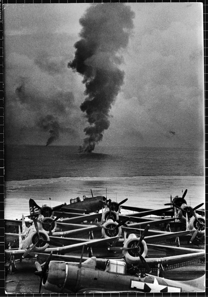 View from the rear deck of a US aircraft carrier, its planes parked on the flight deck, Japanese planes shot down by American fighter squadrons in the background. (Photo by William C. Shrout/The LIFE Picture Collection © Meredith Corporation)