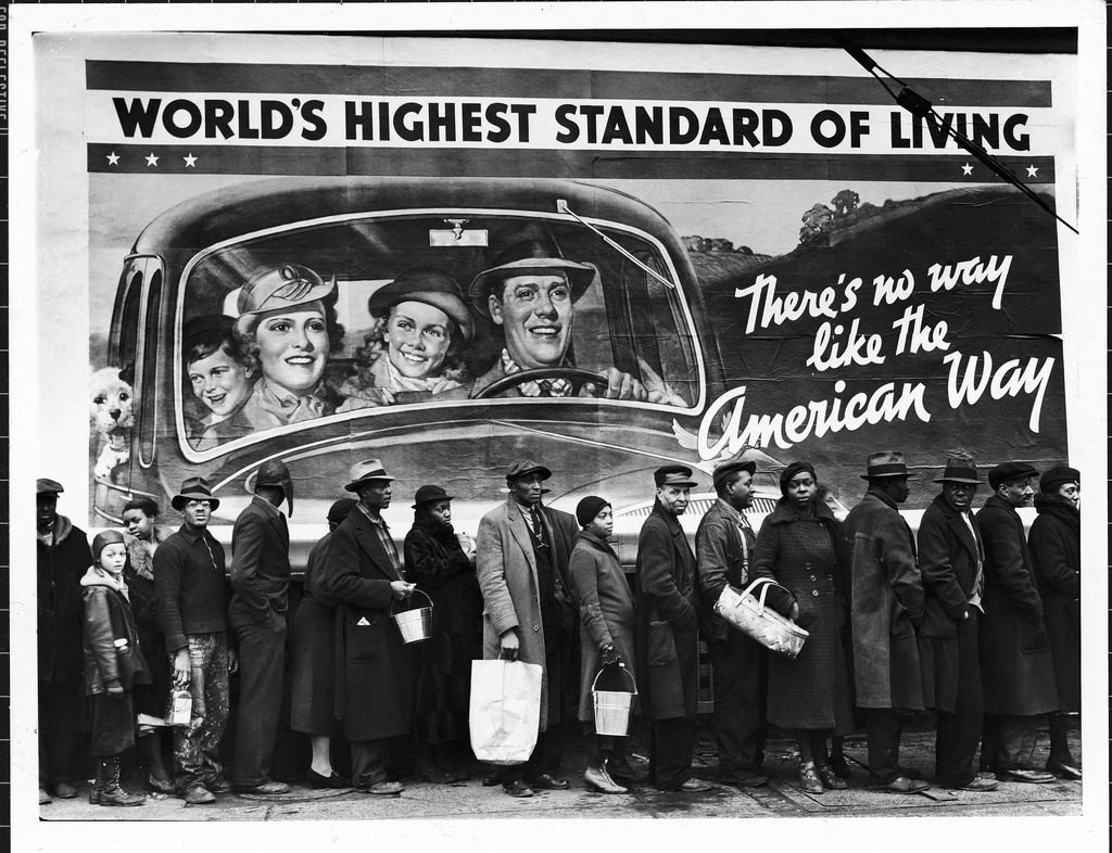 African American flood victims lined up to get food and clothing from a Red Cross relief station in front of an ironic billboard extolling, "World's highest standard of living/ there's no way like the American way." (Photo by Margaret Bourke-White/The LIFE Picture Collection © Meredith Corporation)